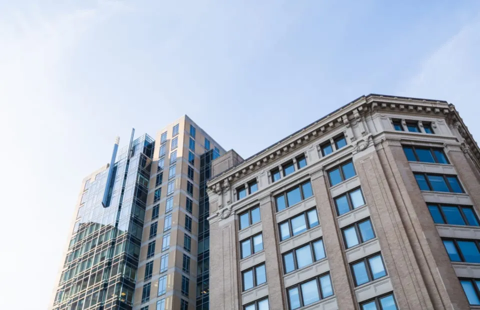 A modern multi-story commercial building in glass and stone against a clear sky.