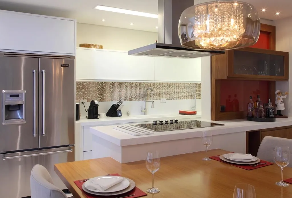 Bright modern white kitchen with a large island, stainless appliances, and a glass pendant fixture.
